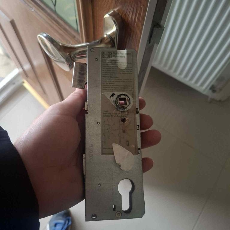 Locksmith inspecting a broken key and stuck door lock